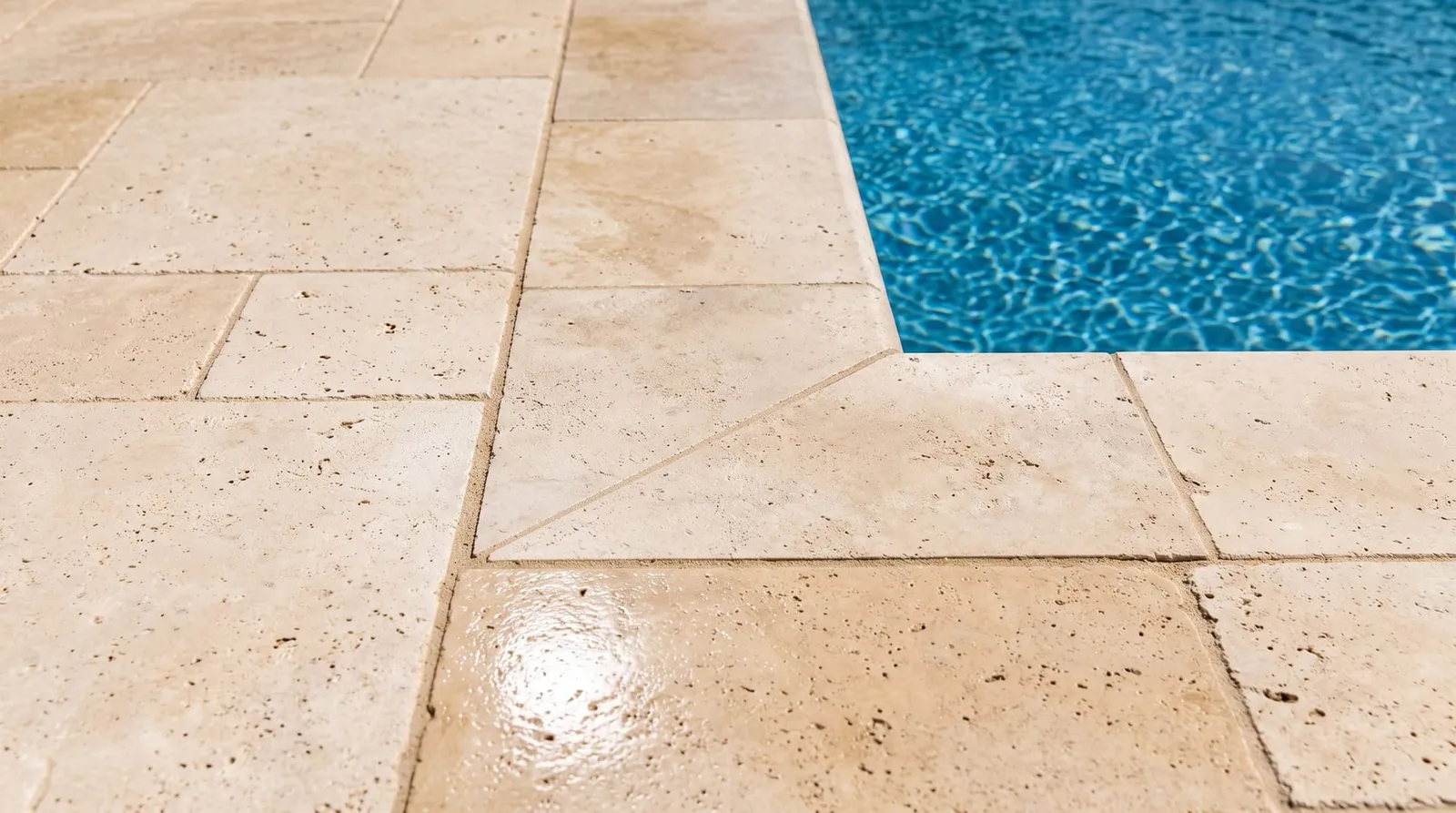 Travertine pool coping freshly sealed, color deepened